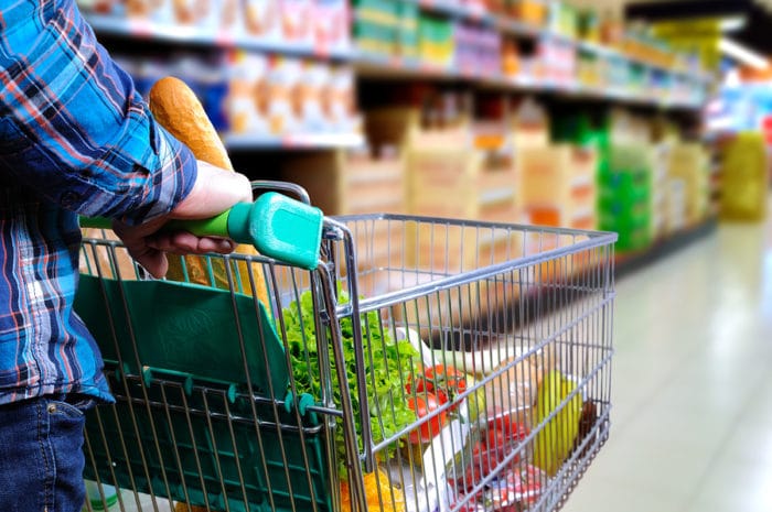 Man Pushing Shopping Cart In The Supermarket Aisle
